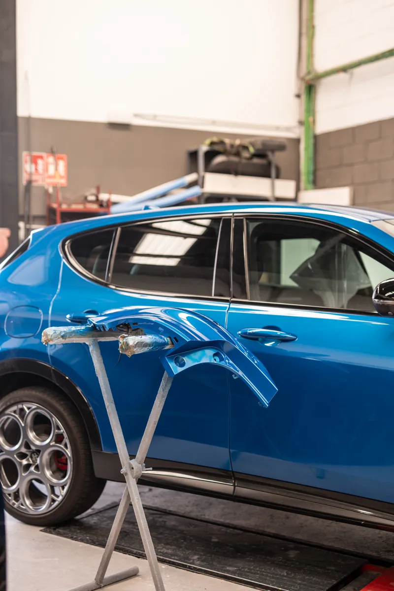 Alfa Romeo azul junto a sus piezas recién pintadas en el mismo color